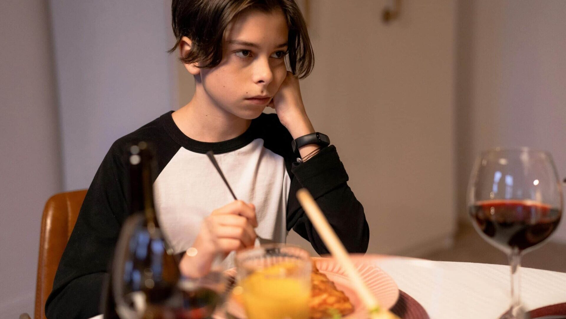 Young boy looking sad while eating a meal.