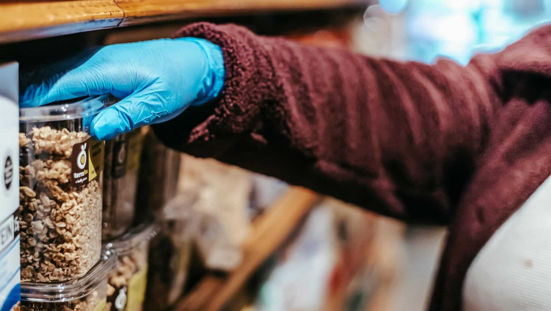 Female customer choosing a box of granola from a grocery store shelf during a shopping trip