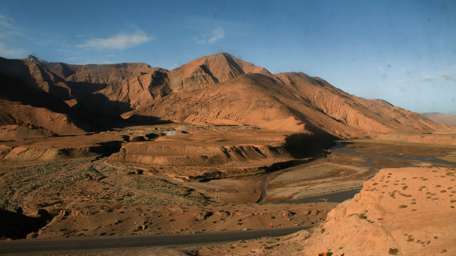 River winding through dry terrain with mountains in the distance