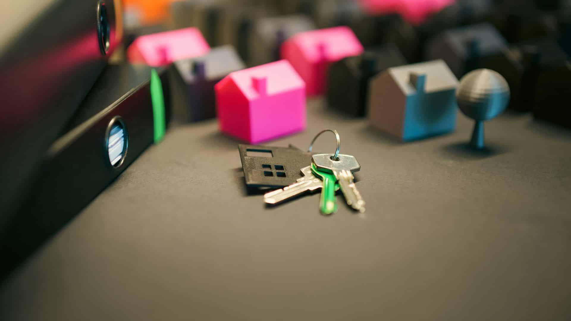 Miniature model houses with keys placed on a desk surface