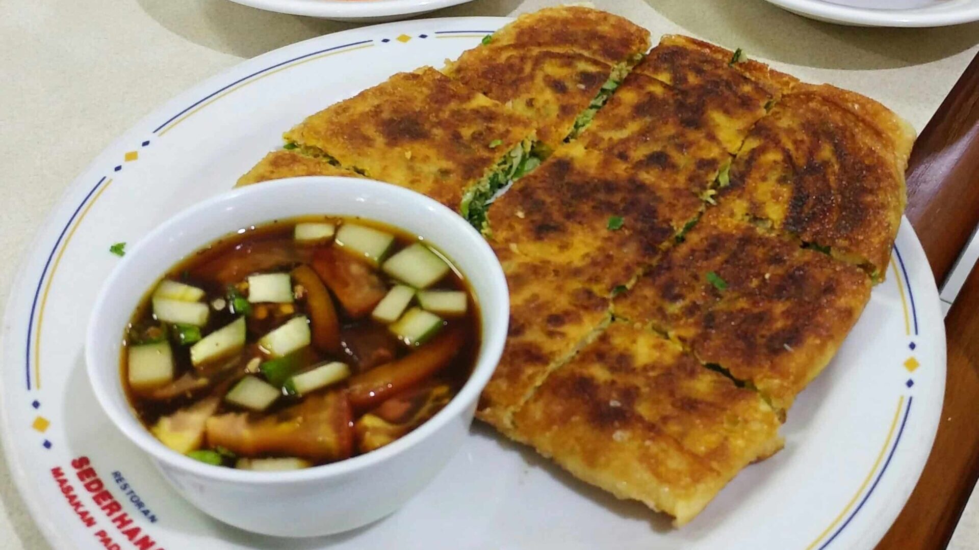 White plate with a sandwich served alongside a bowl of soup.