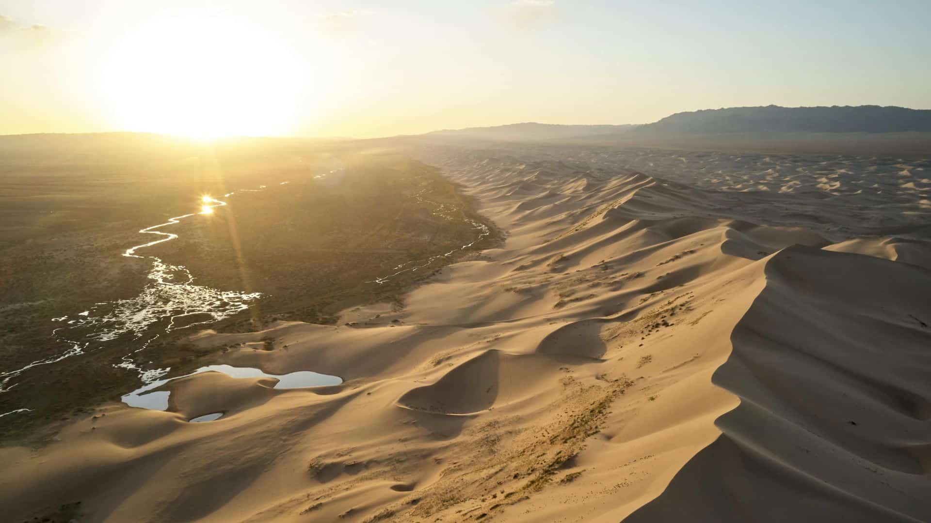 Sunlight breaking through clouds over desert terrain at sunset