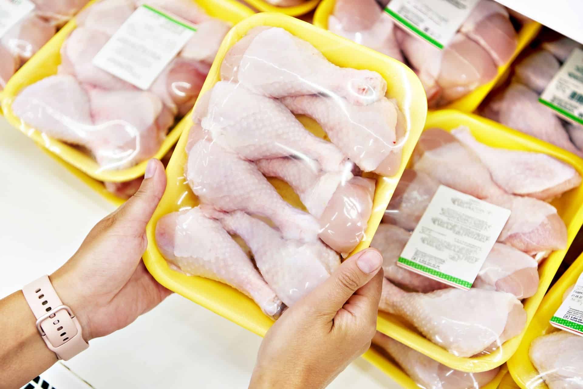 Person holding a pack of chicken leg meat in store
