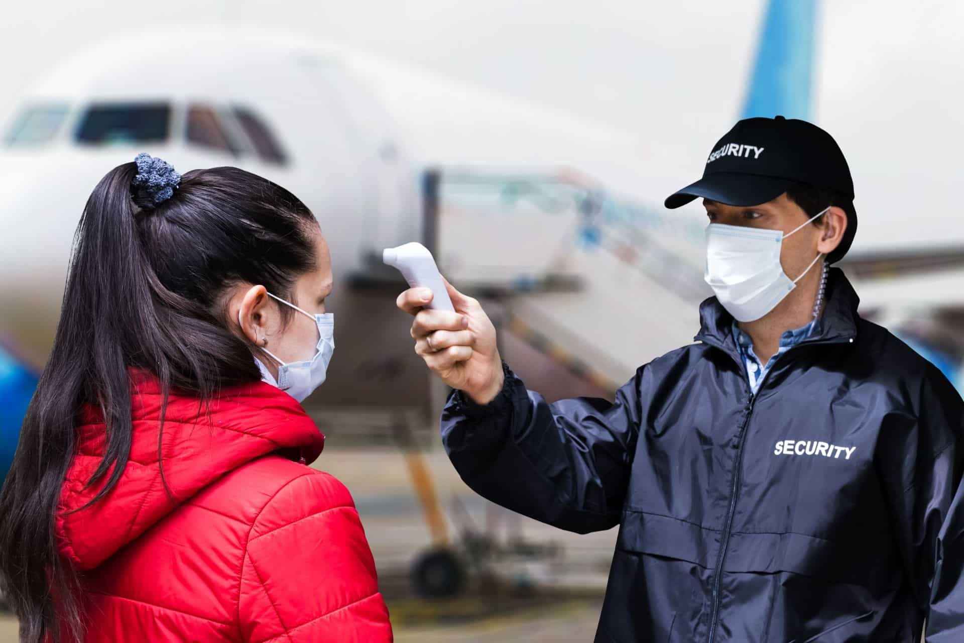 Airport security checking a person's temperature before boarding the plane