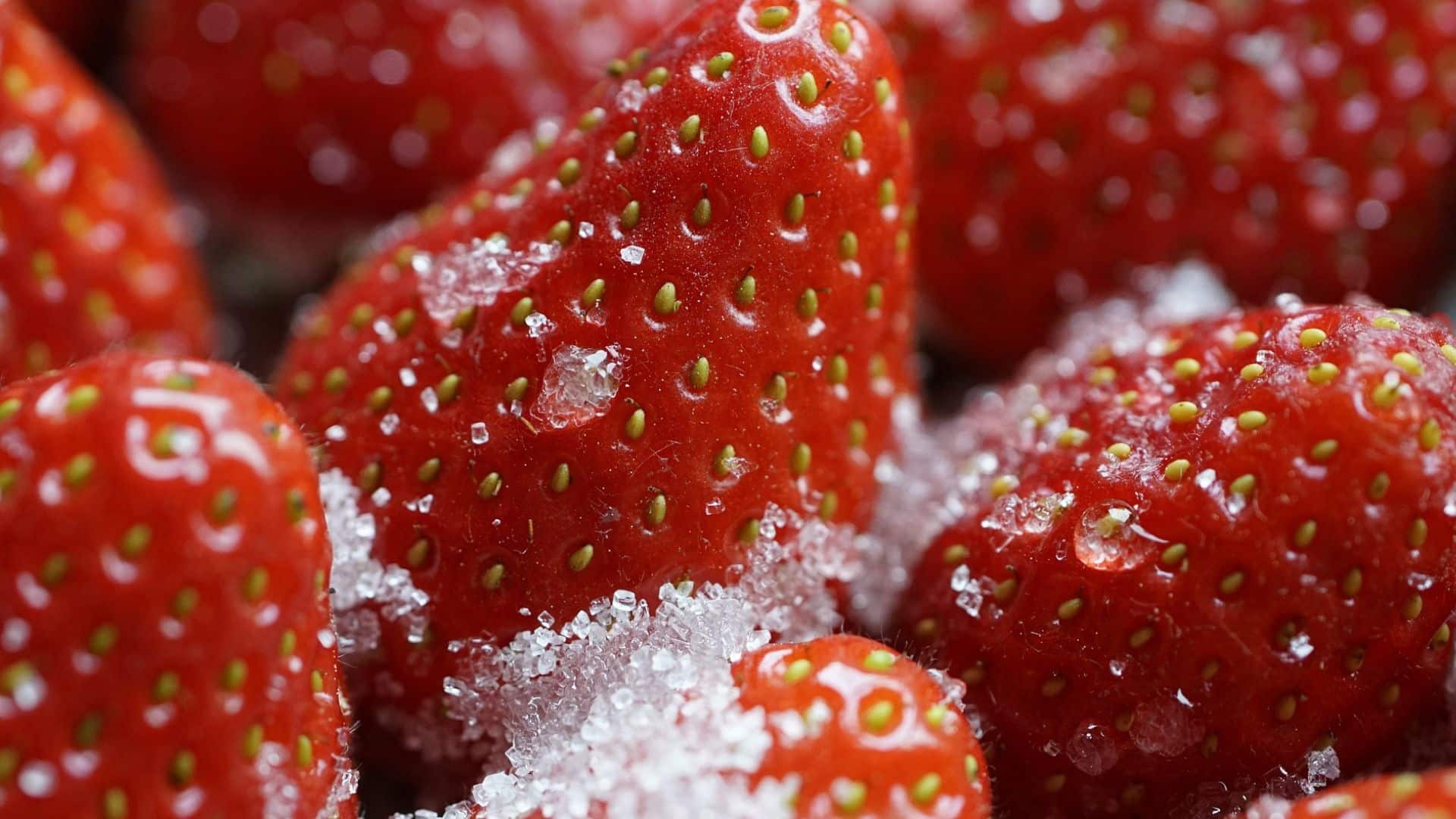 Close-up of fresh strawberries coated in sugar crystals.