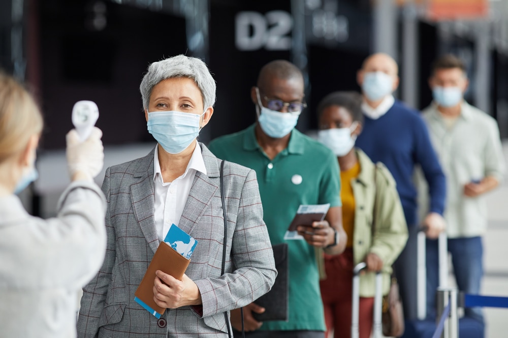 Group of people in mask standing in a row and testing they are at the airport