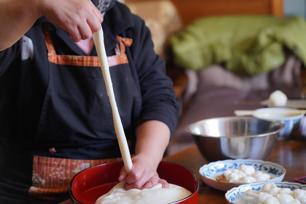 A woman mixing ingredients with freshly pounded mochi