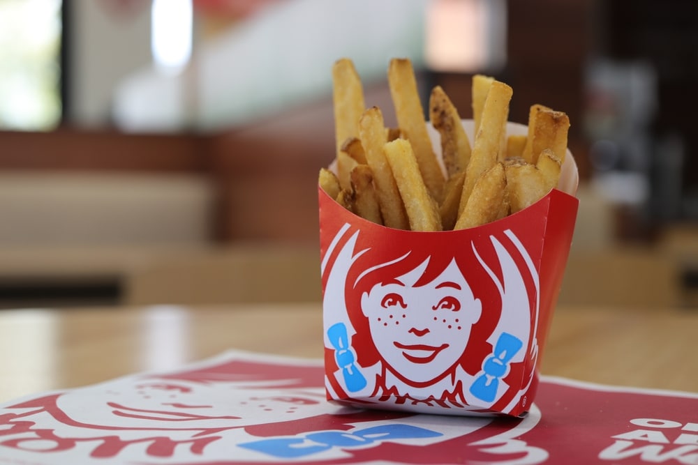 Wendy’s French fries in branded red container placed on table inside restaurant.