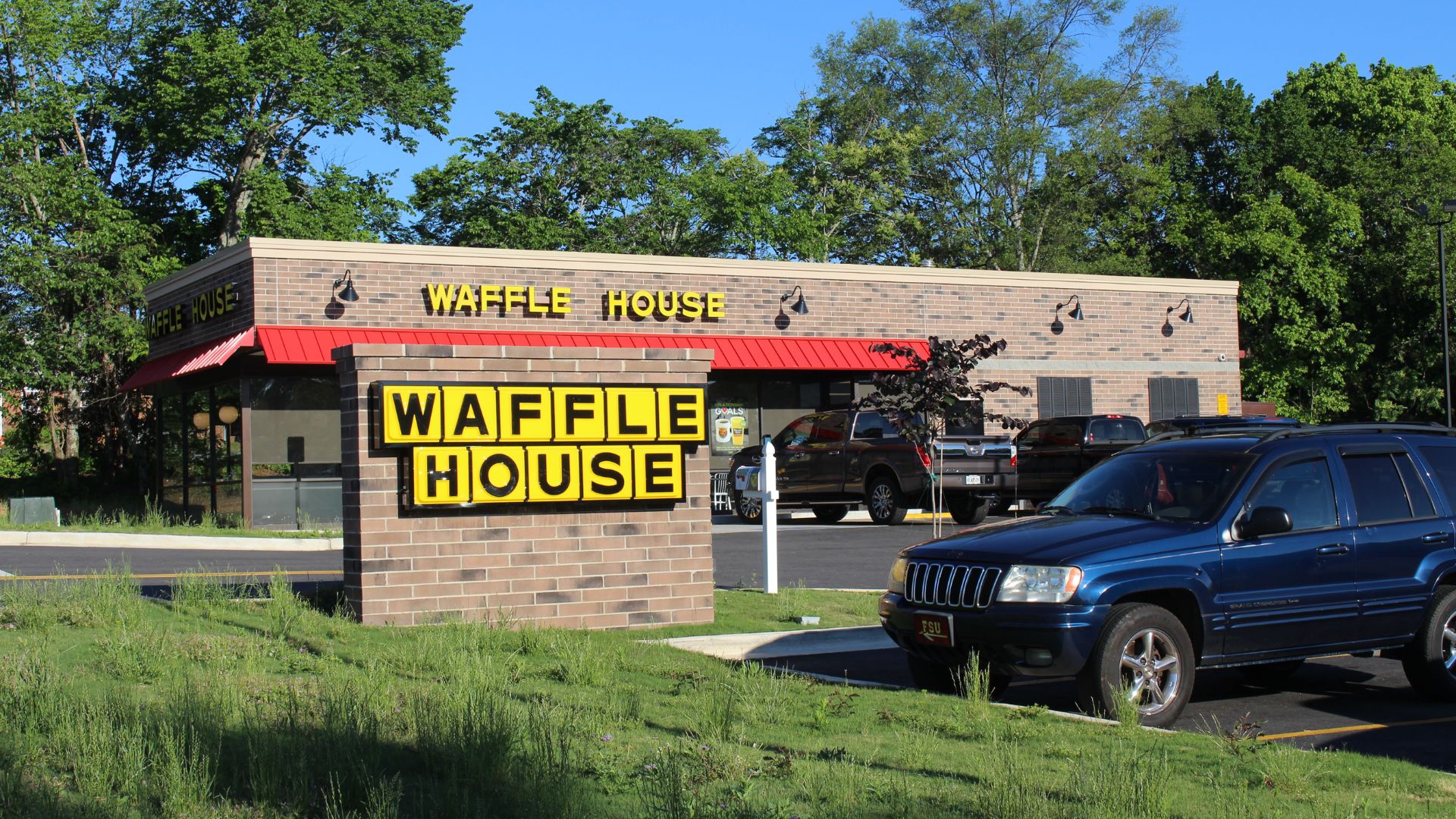 The exterior of a Waffle House restaurant with a large yellow Waffle House sign in front.