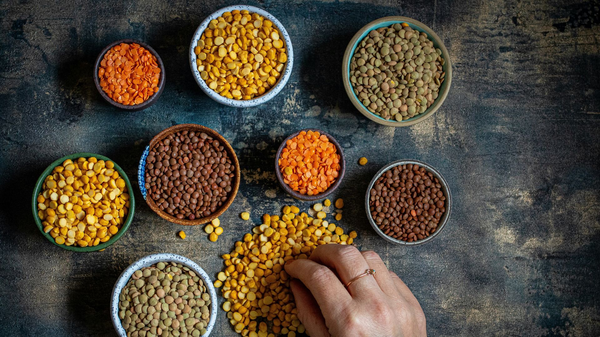 Person touching a bowl of lentils on a table