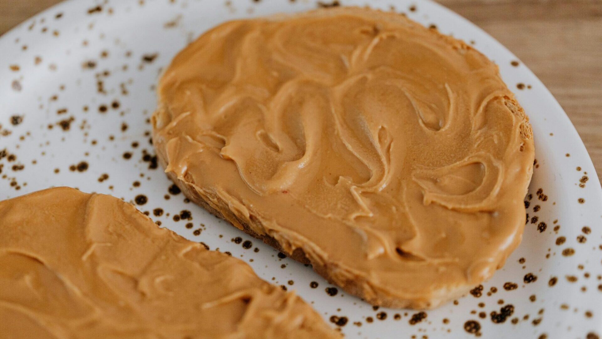 Close-up of toasted bread spread with creamy peanut butter on a plate.