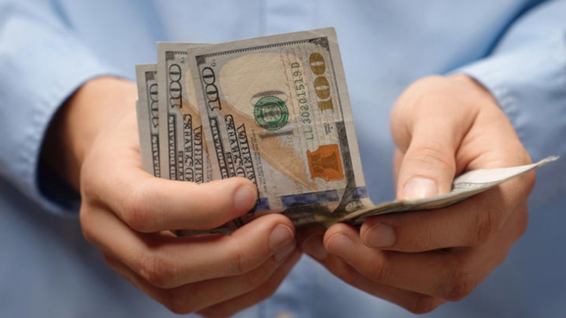 Close-up of someone holding a few $100 bills.