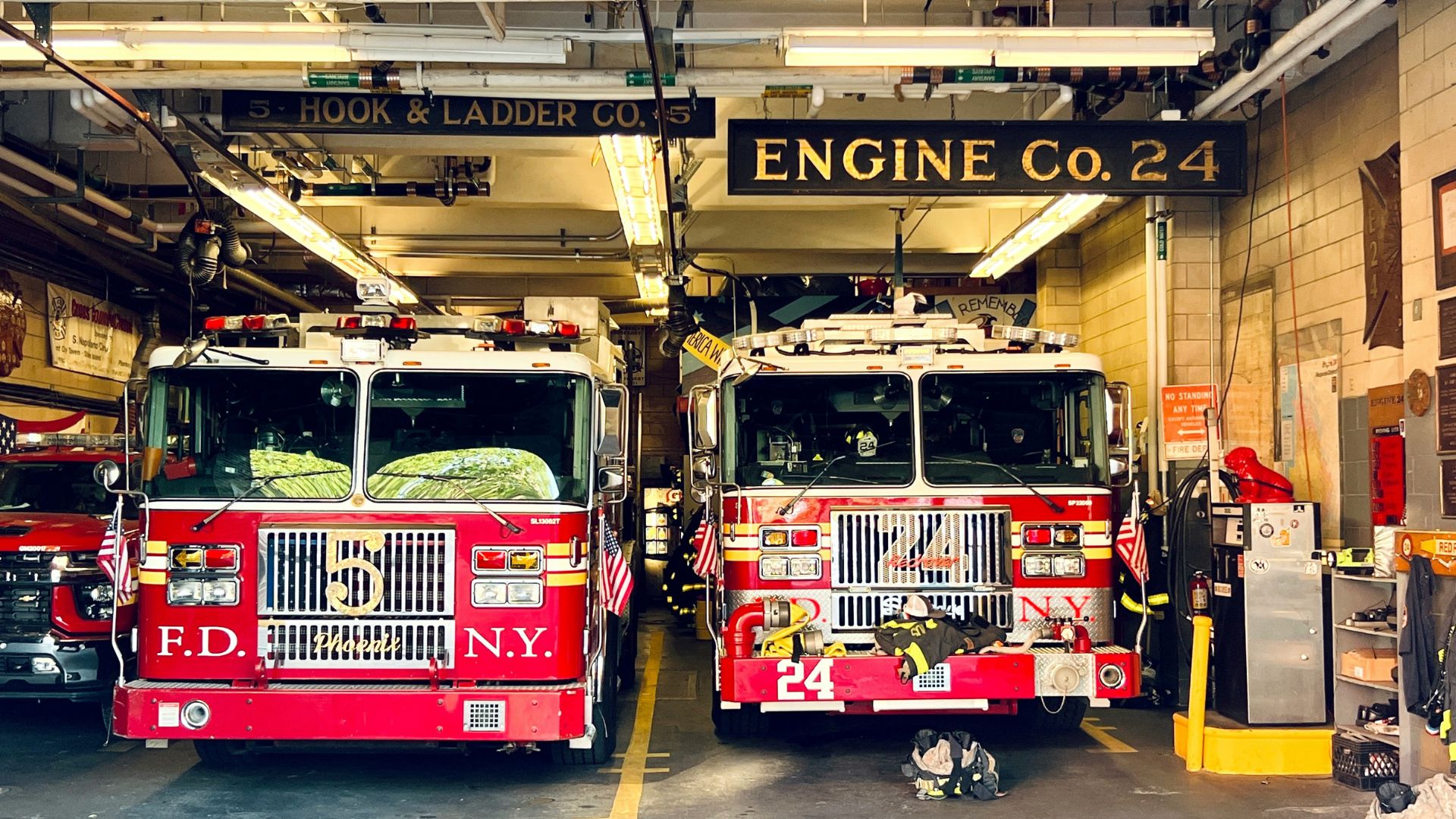 Two fire trucks parked inside a fire station garage with equipment visible
