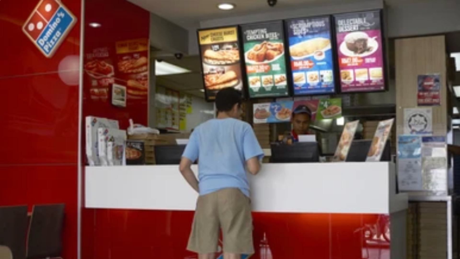 Customer ordering food at a Domino’s counter.