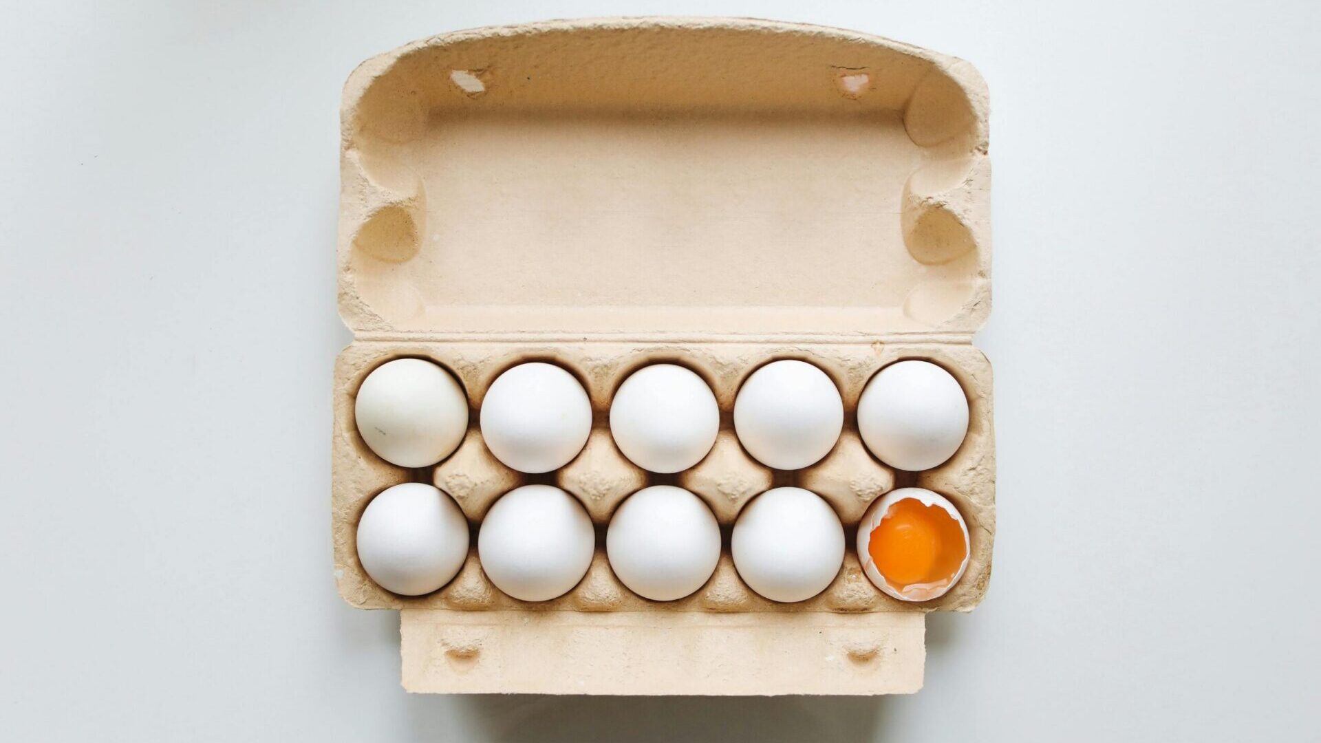 White eggs arranged in a cardboard tray on a kitchen surface.