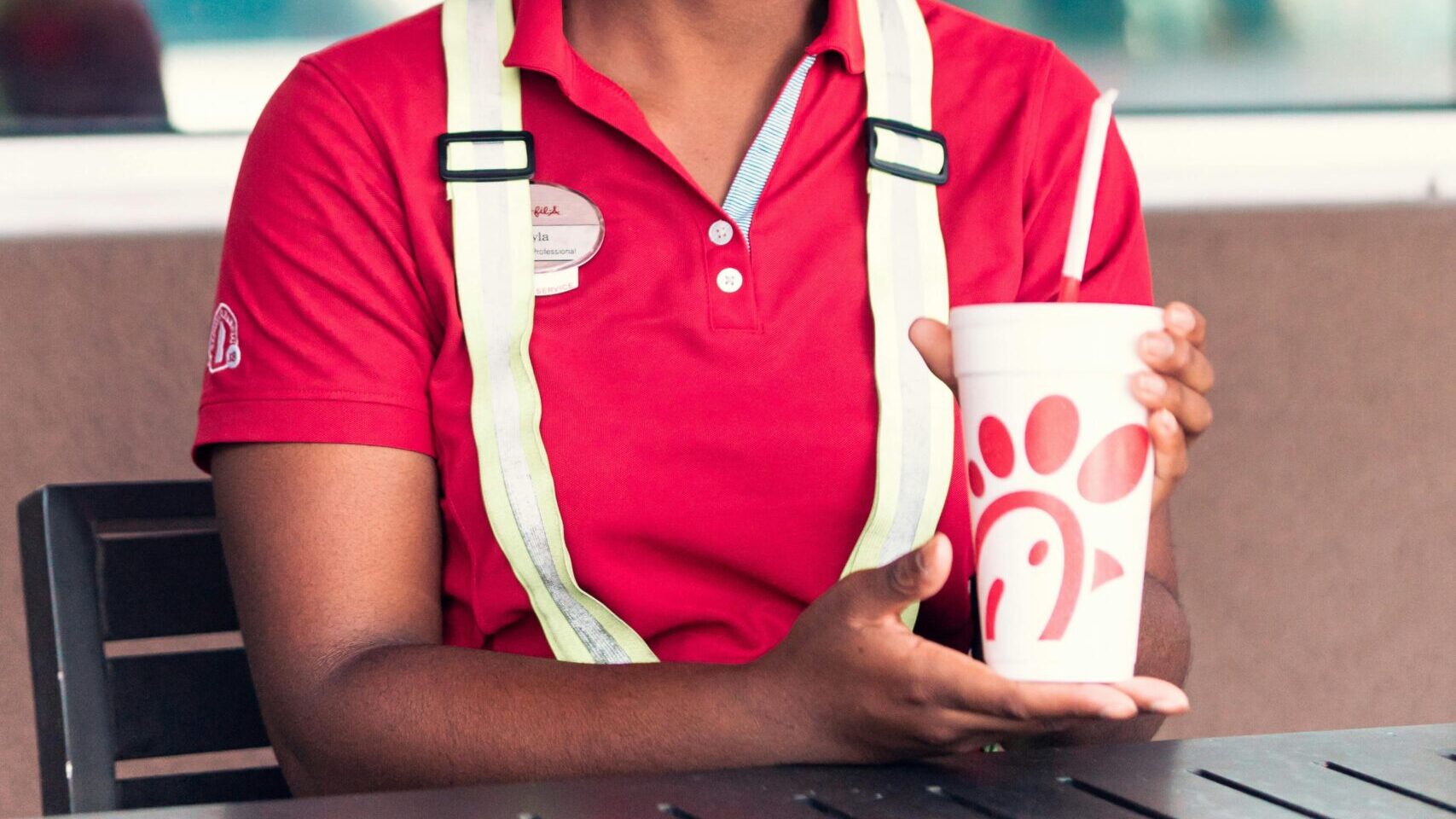Smiling woman holding a drink while standing outdoors.