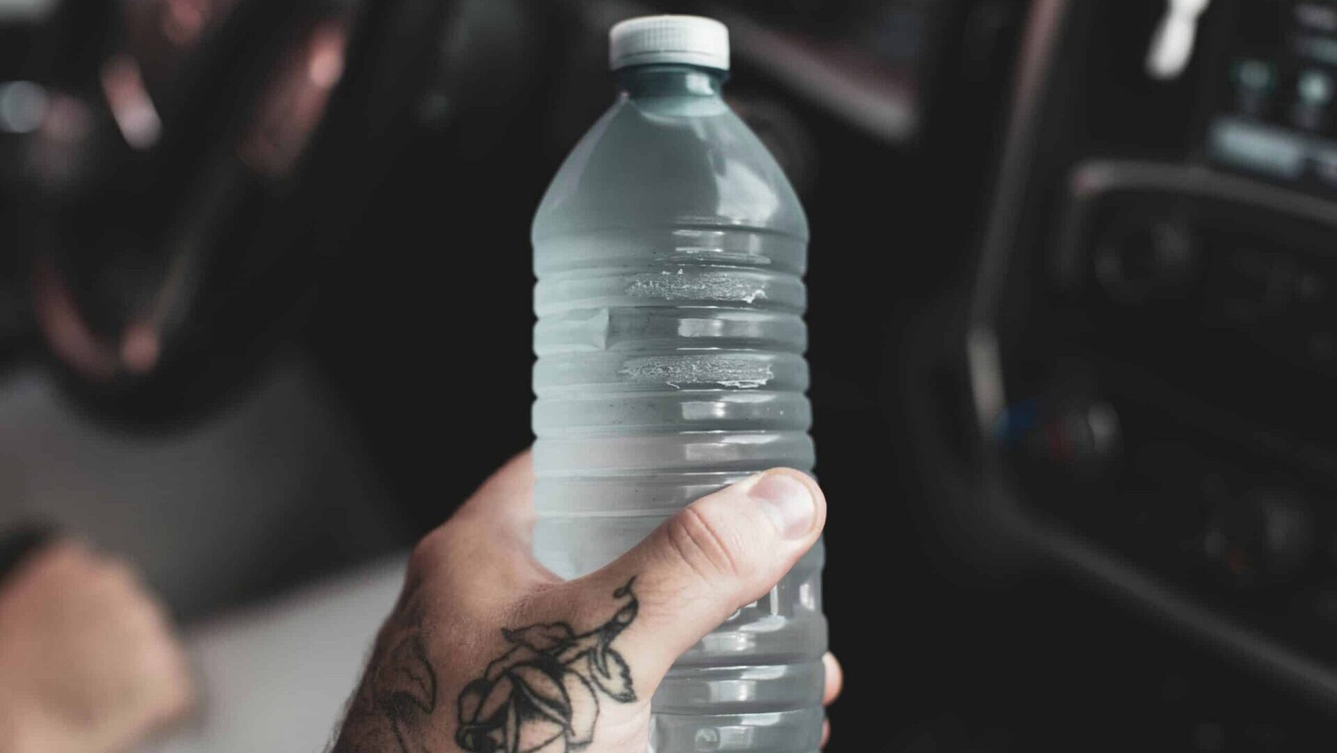Person holding a clear plastic water bottle in their hand, with focus on hydration and everyday water consumption.