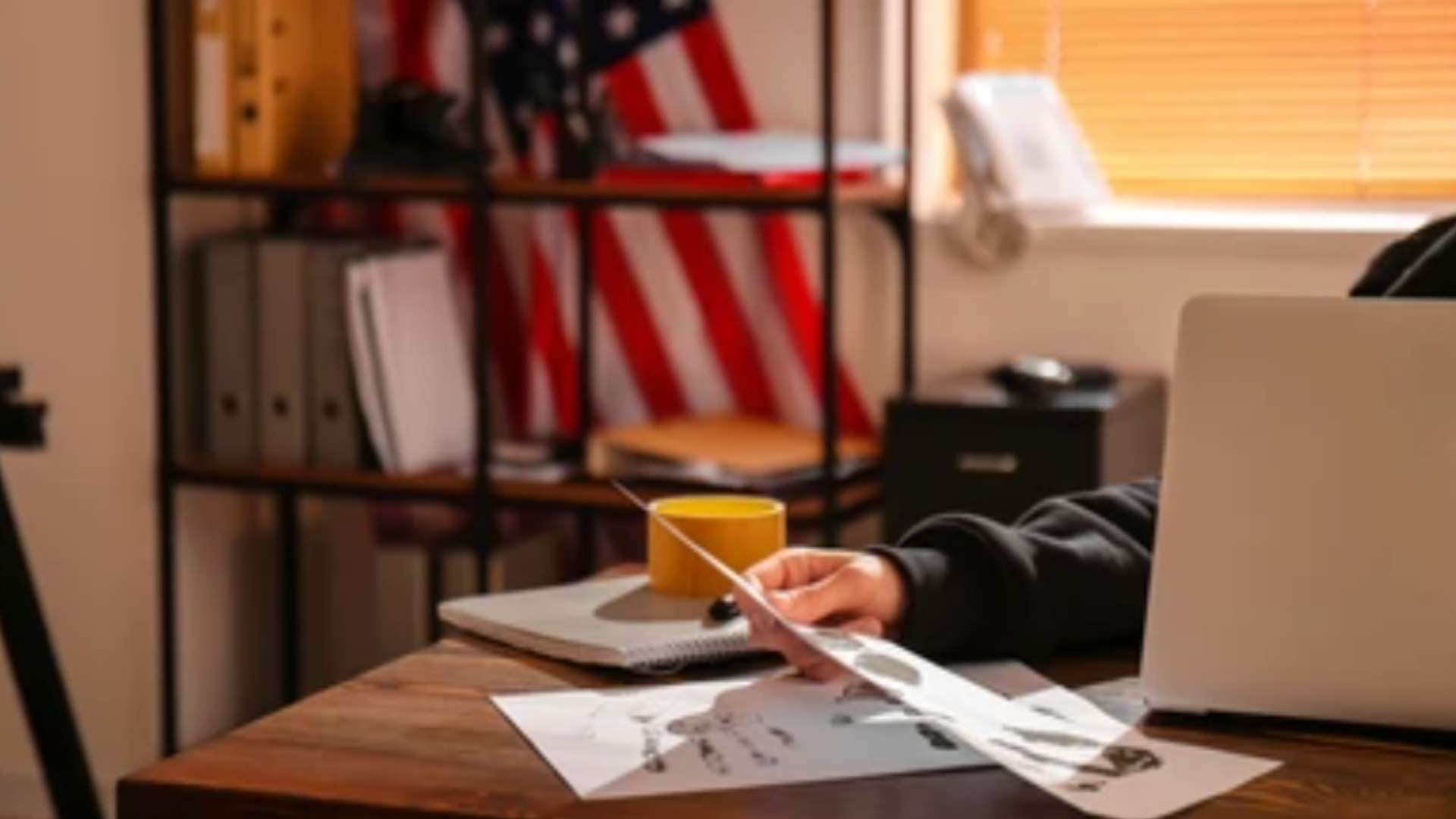 Person reviewing documents at a desk with an American flag in the background.