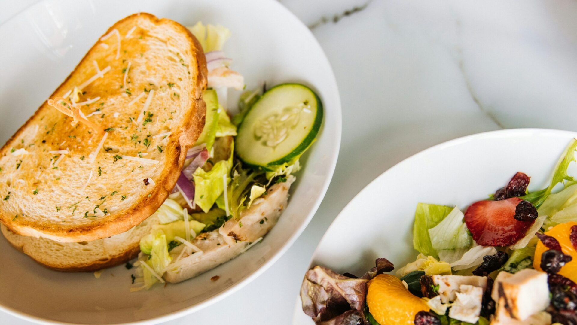 Fresh salad and sandwich served on white plates, arranged on a table for a light meal.