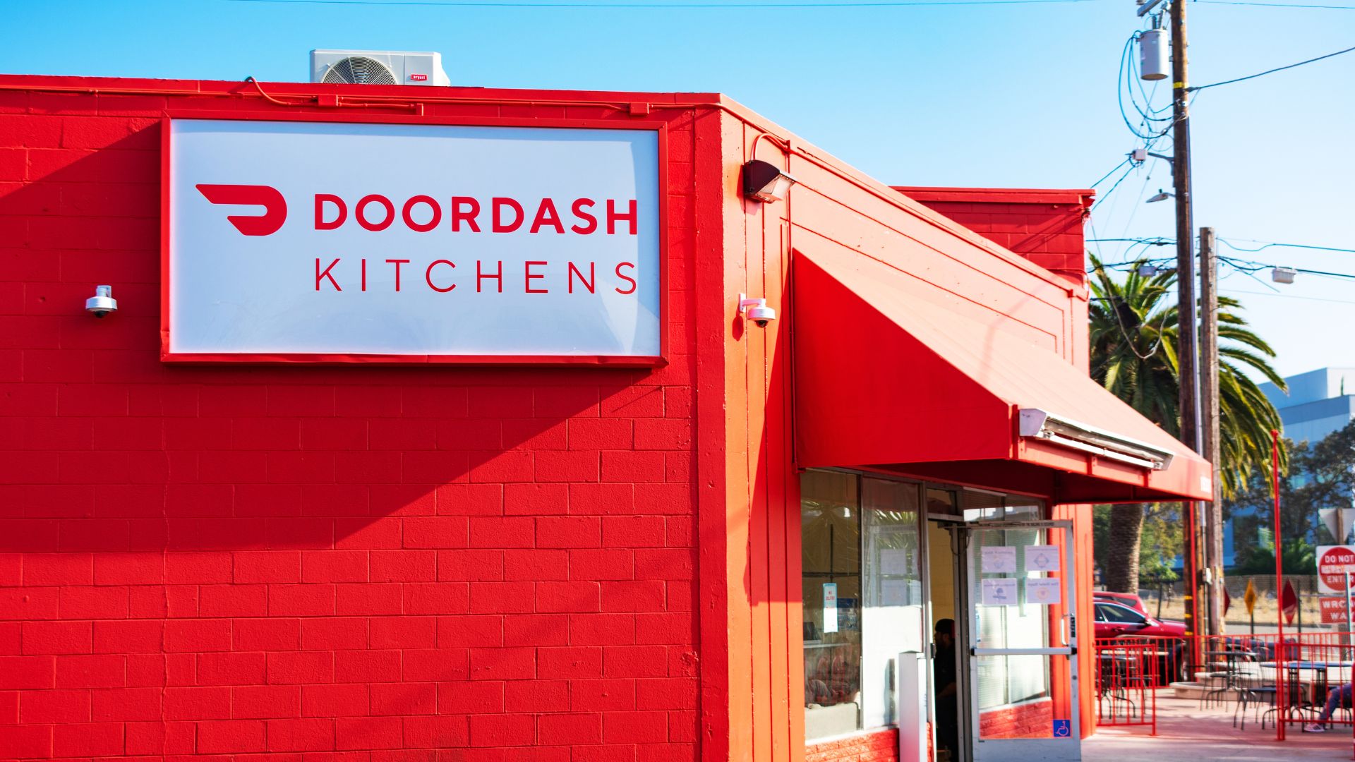 Exterior view of a red DoorDash Kitchens storefront with white signage.