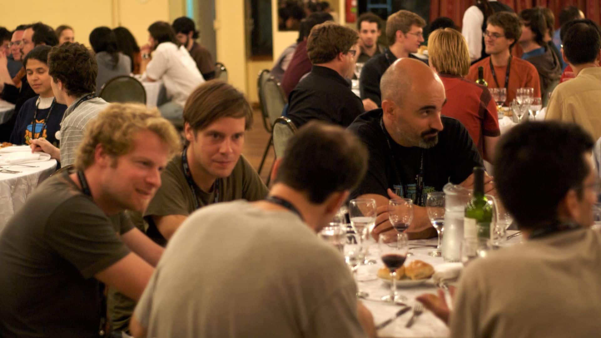 Several people are seated around a table engaged in conversation during a communal meal.