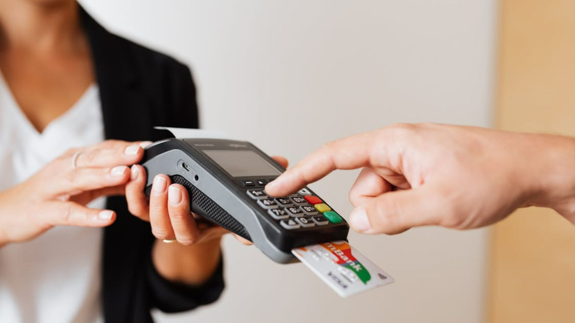 A person holds a card machine while another inserts a card and processes a transaction
