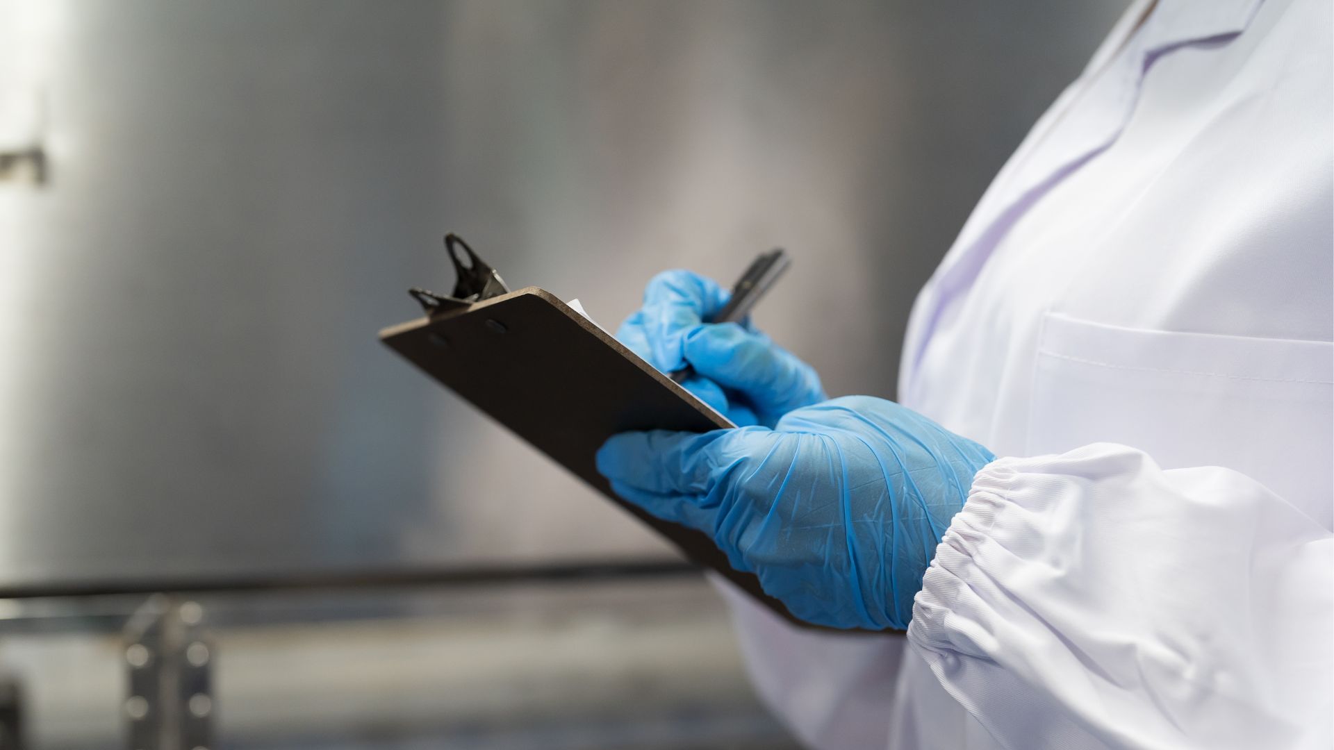 Hands of worker working and inspecting, taking notes on a clipboard.