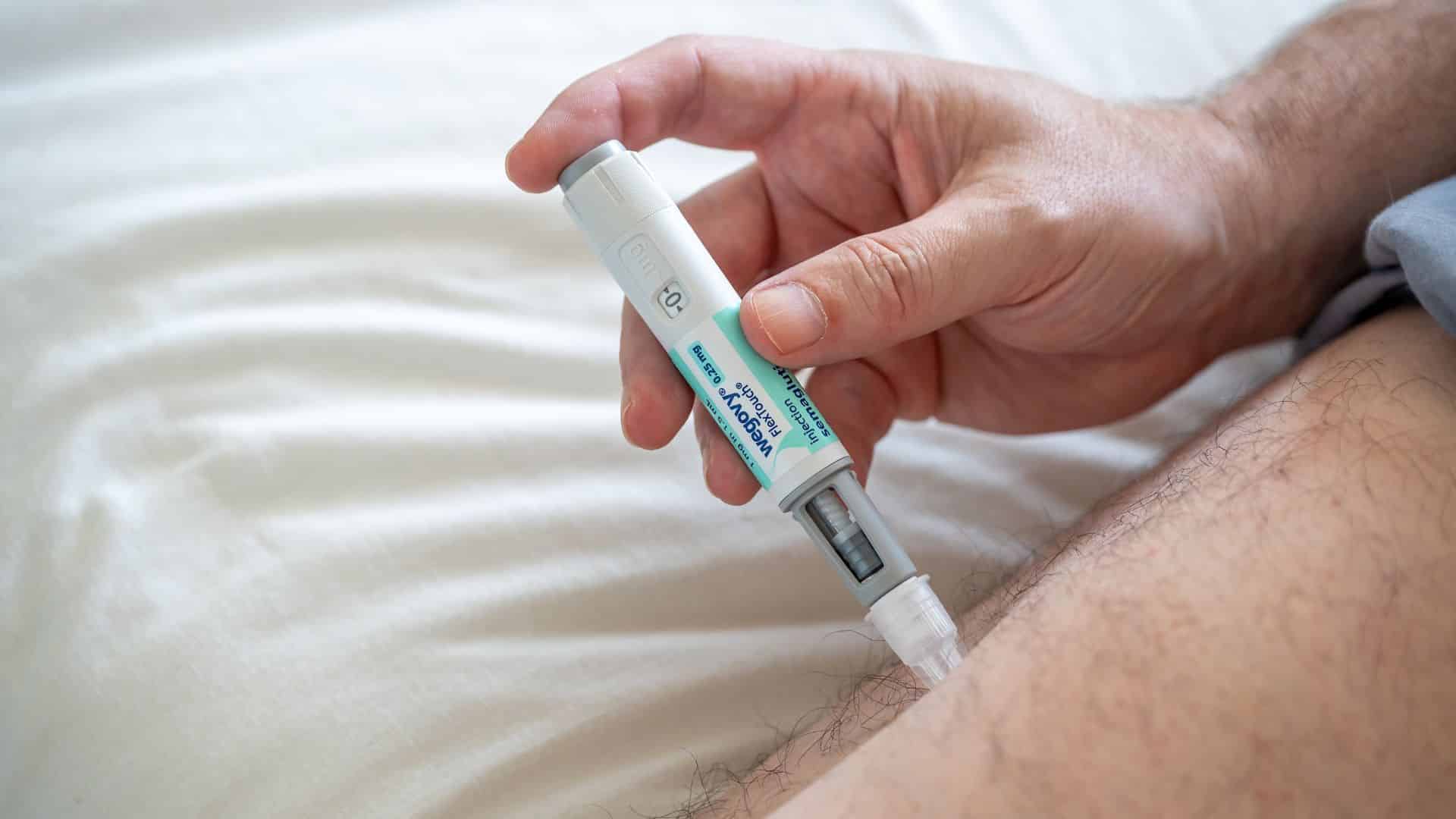 Man using a Wegovy injection pen for weight loss treatment