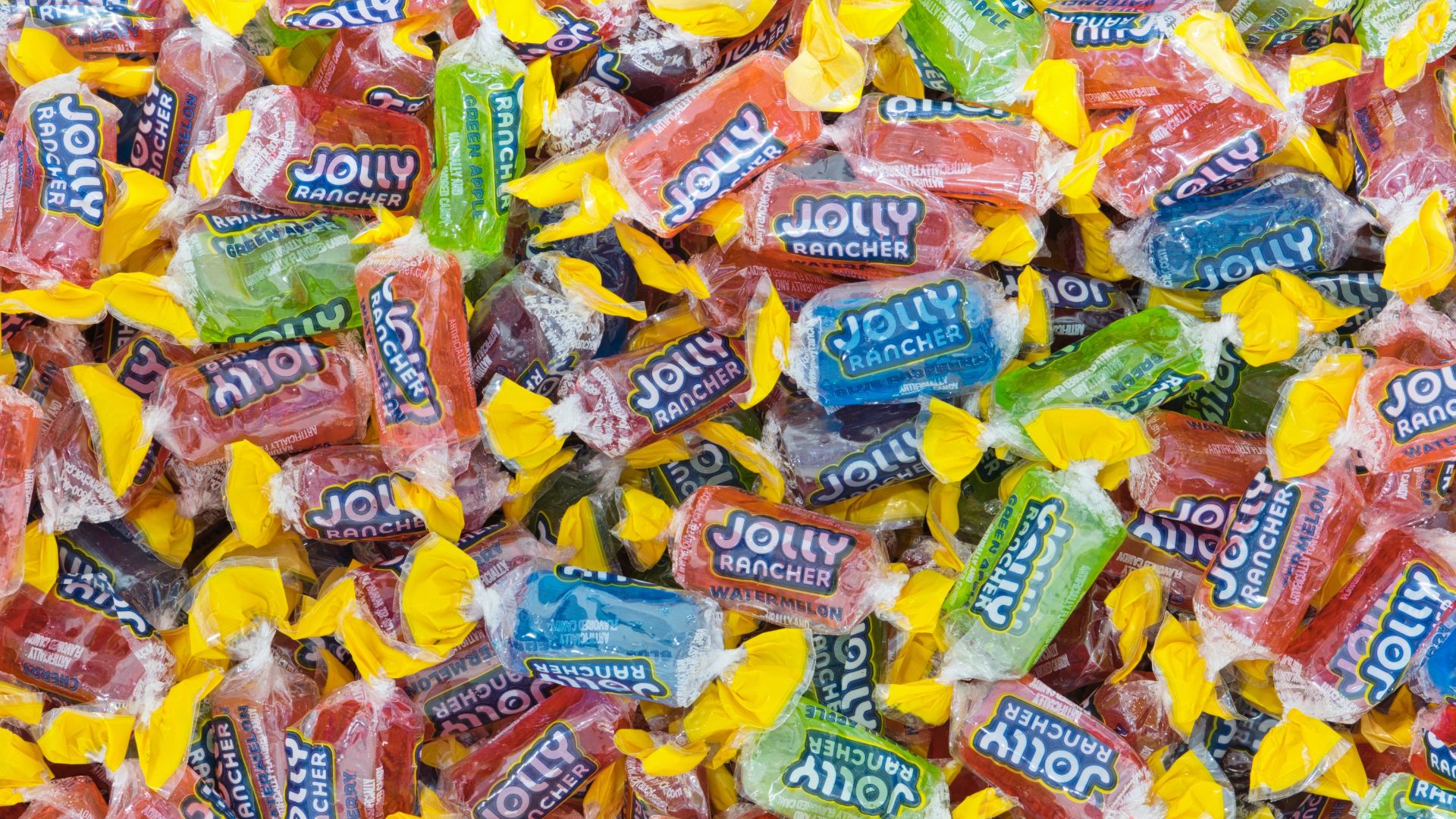 Jolly Rancher hard candy in wrappers, assorted flavors scattered