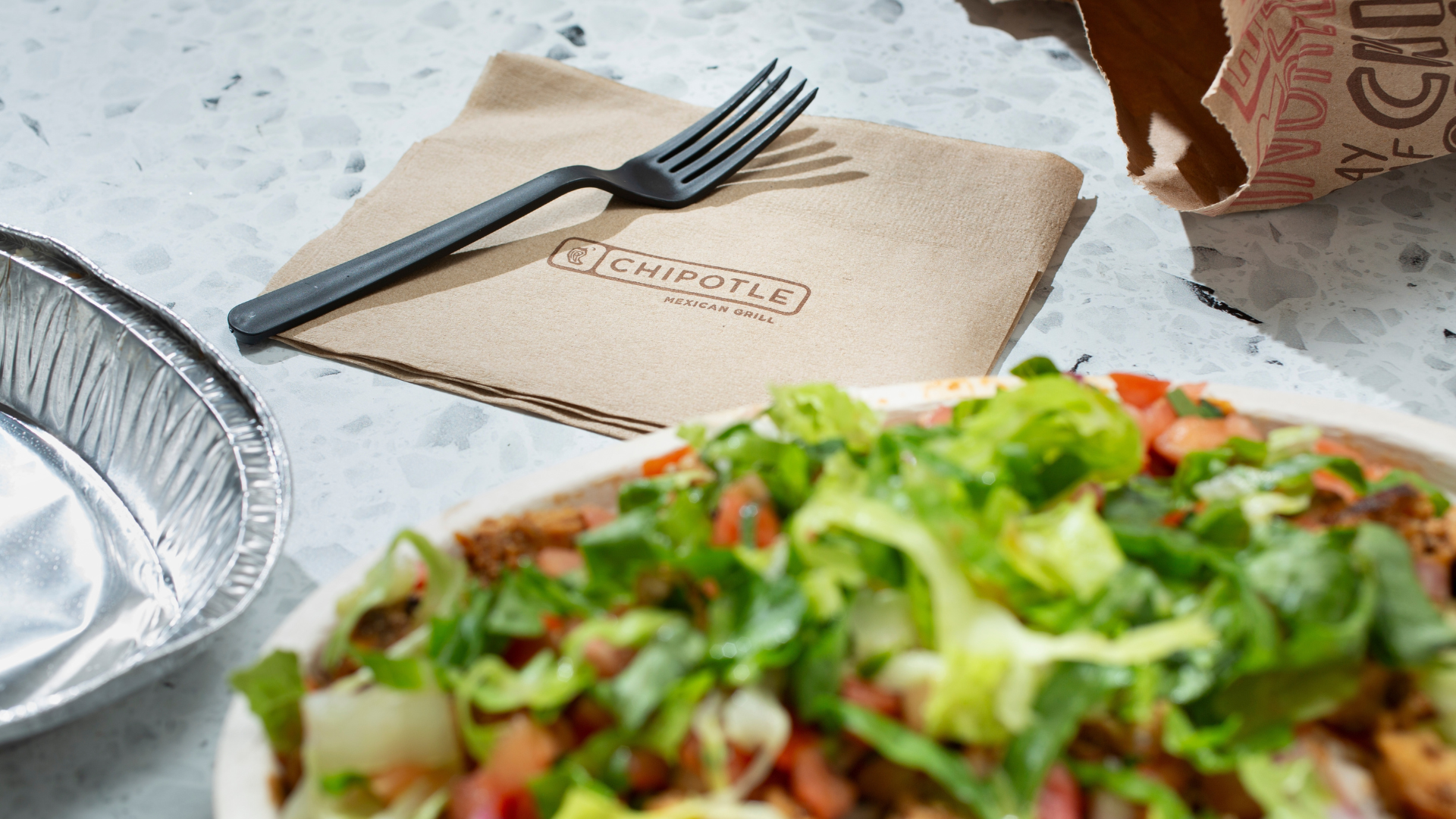 Chipotle bowls with tissue and fork on the background