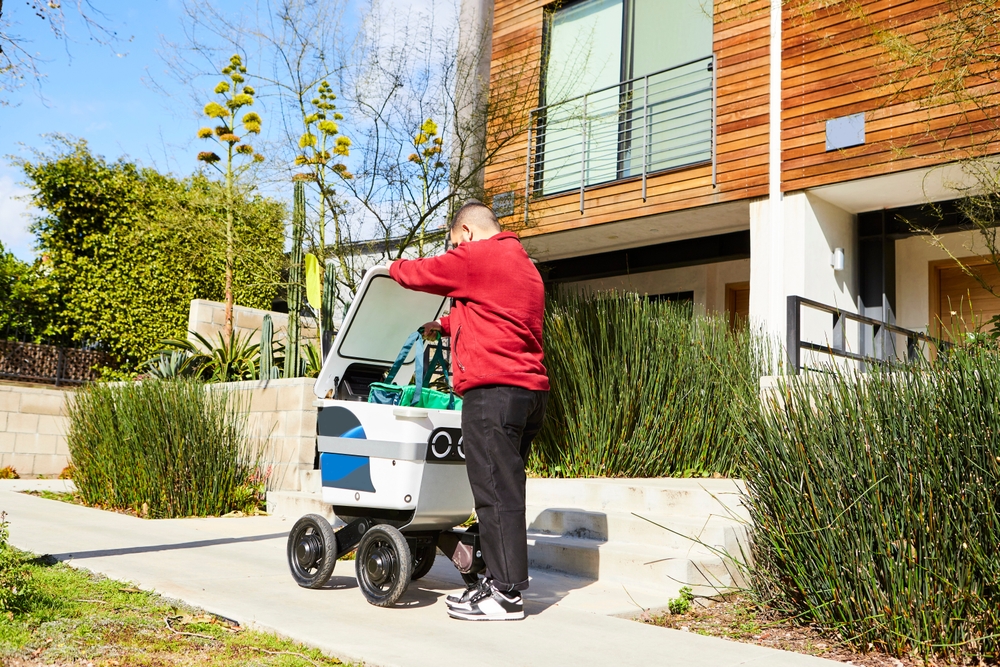A man getting his order from a delivery robot.