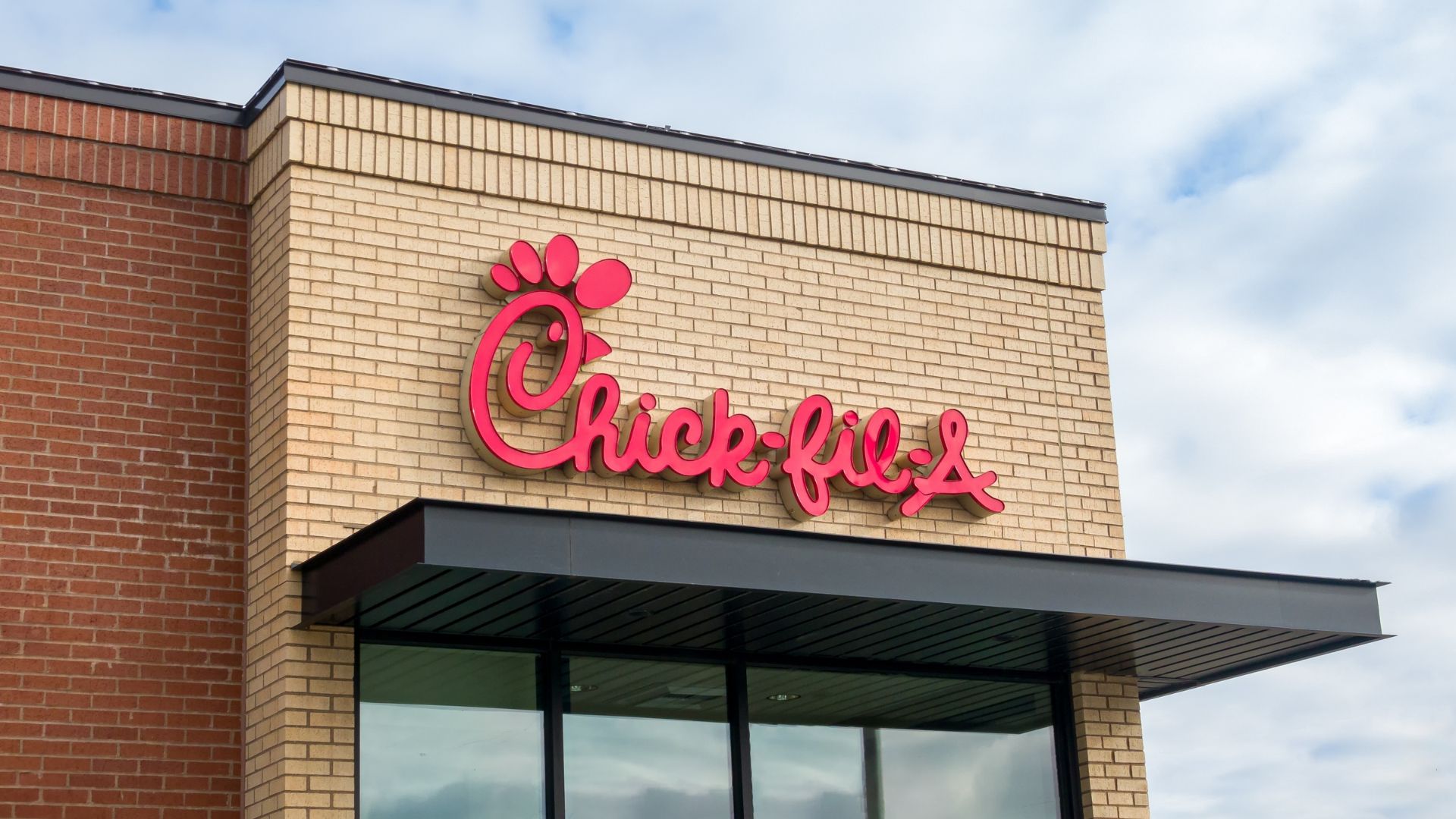 Chick-fil-A restaurant building with red logo sign on brick exterior wall.