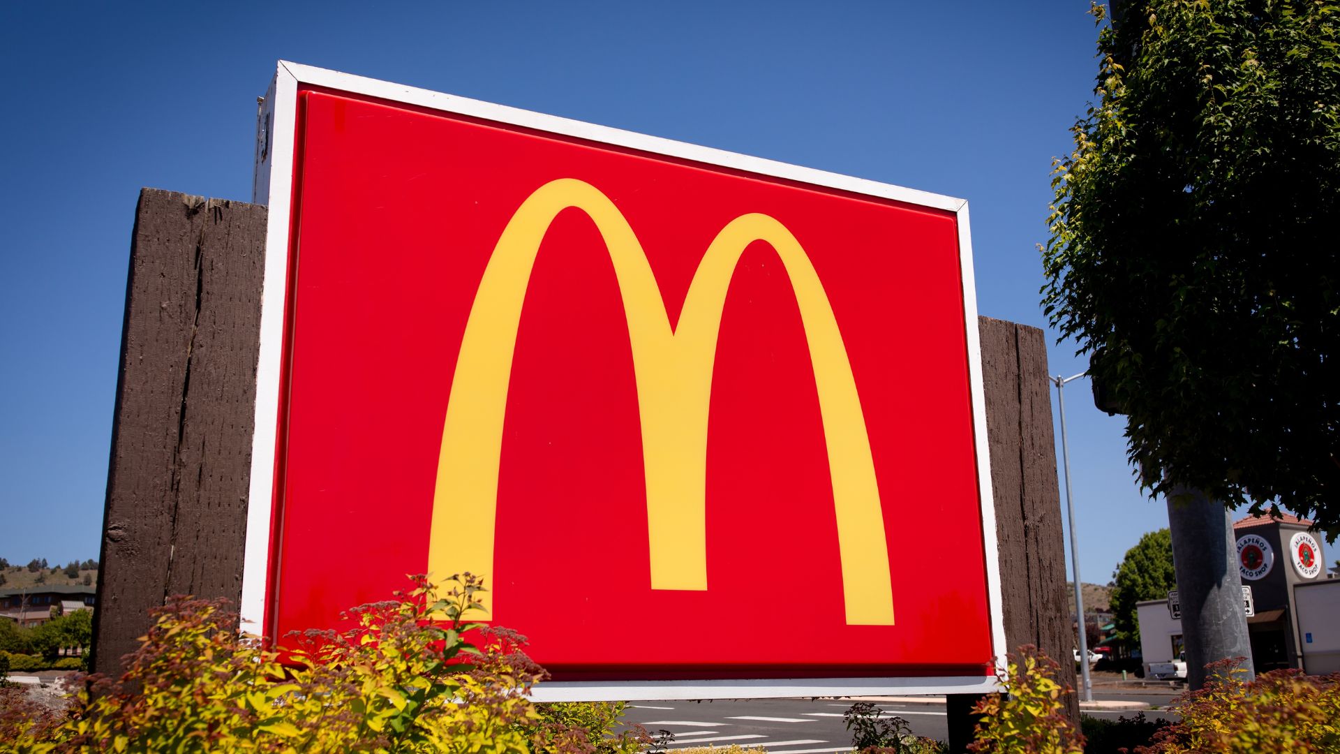 McDonald’s golden arches sign displayed outdoors against a clear blue sky.
