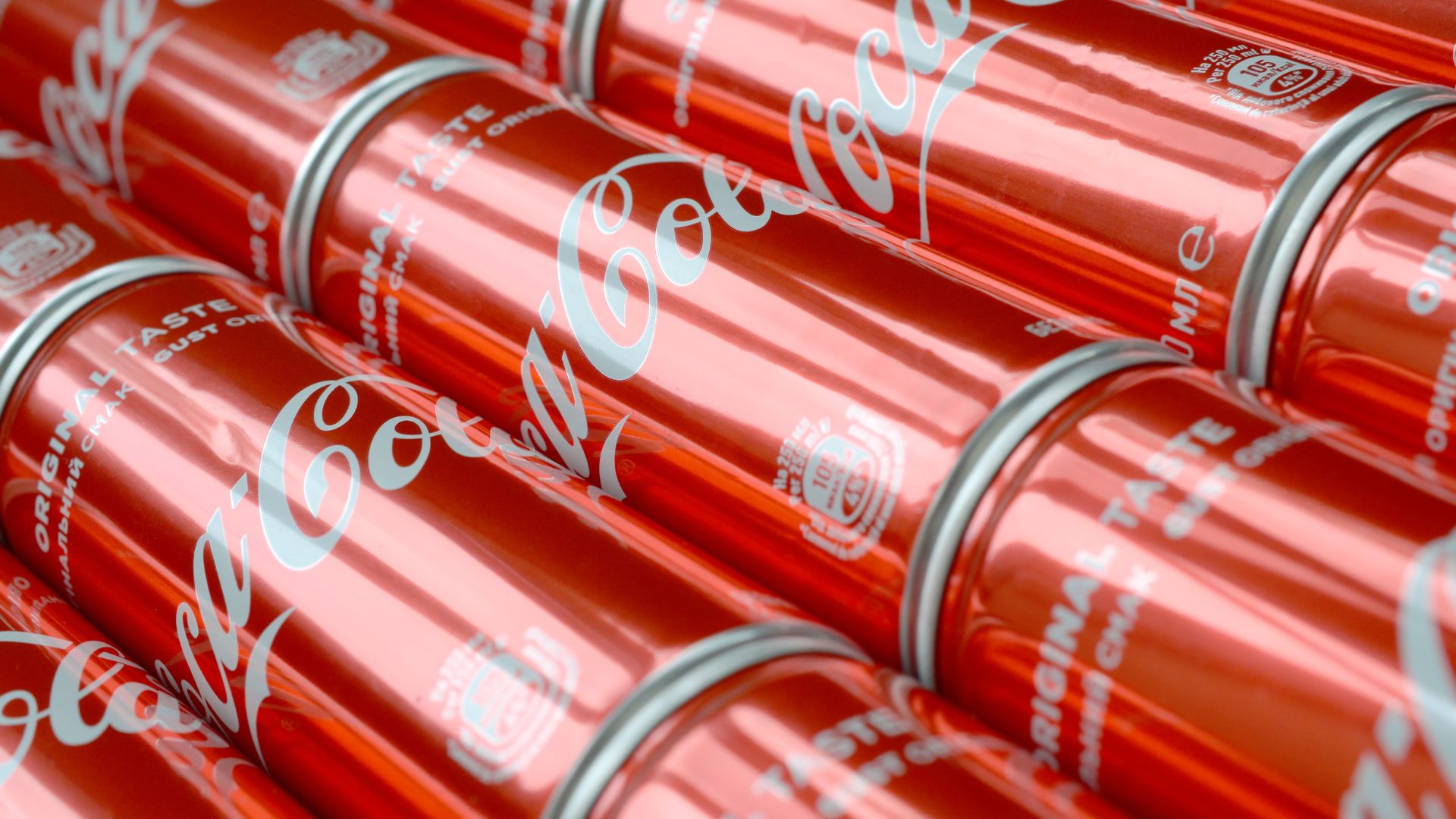 Rows of red Coca-Cola cans with the brand logo printed on aluminum packaging.