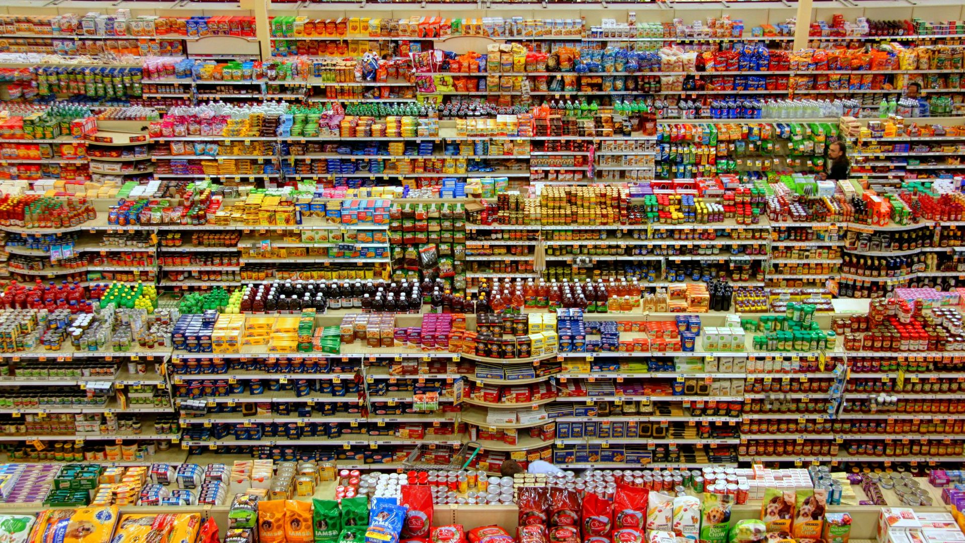 Wide view of supermarket shelves stocked with packaged foods and grocery products.