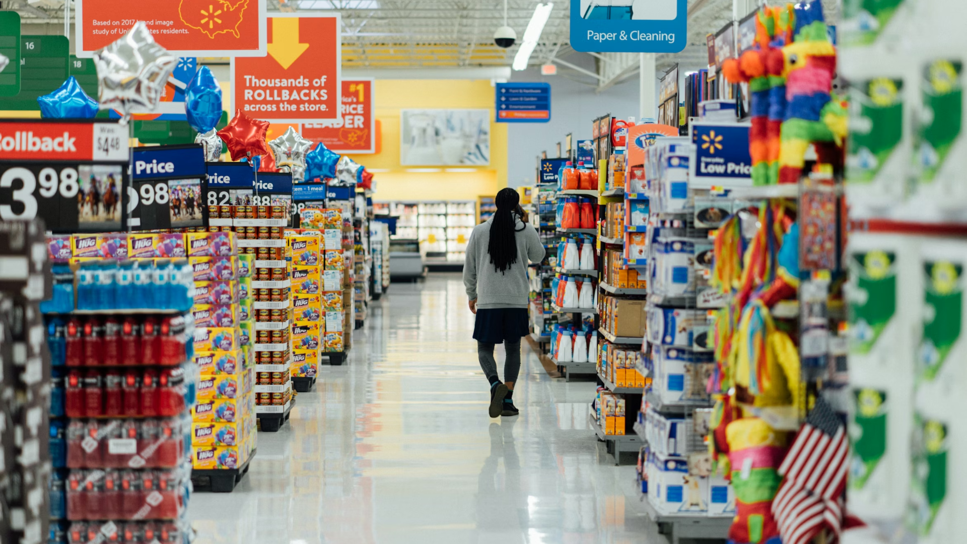Person walking down an aisle inside a large grocery store.