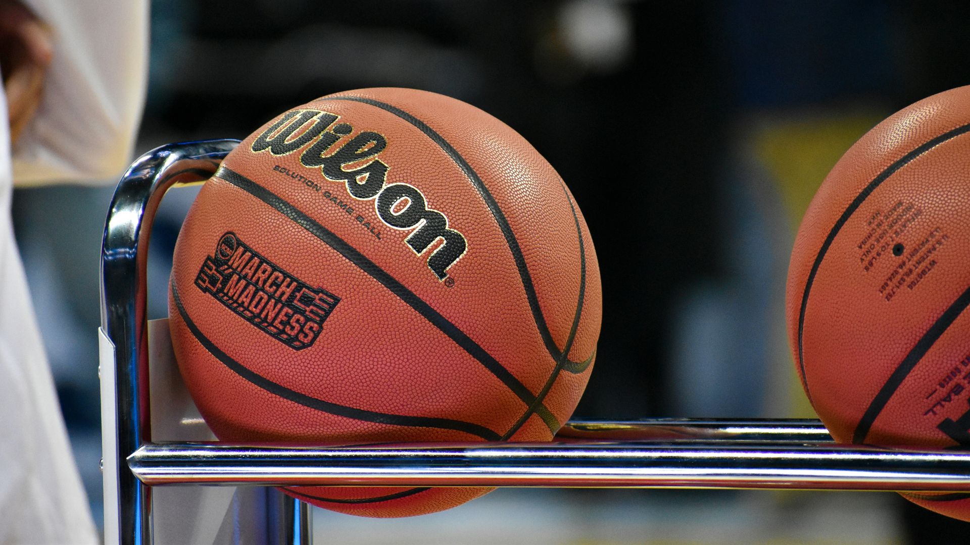 Wilson basketball with March Madness branding resting on a rack near the court
