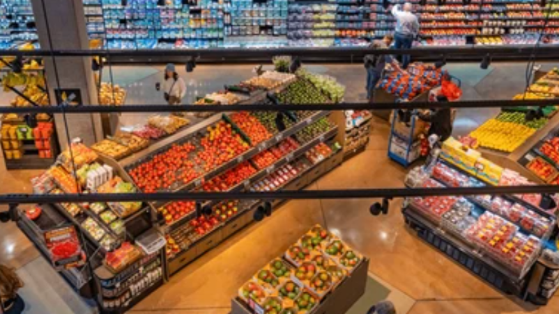 High-angle interior view of a well-stocked grocery store produce section with various fruits and vegetables on display.