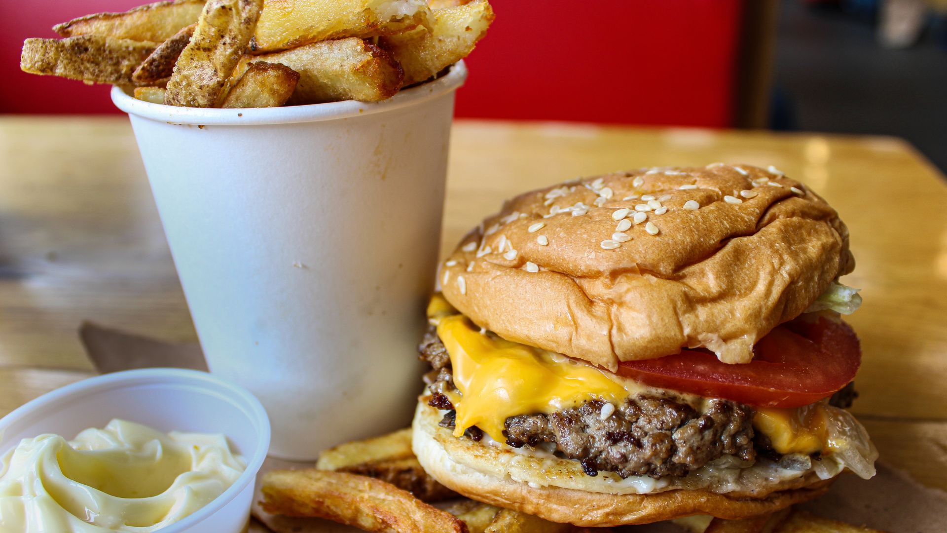 Cheeseburger with melted cheese, tomato, and sesame bun served with fries and dipping sauce.