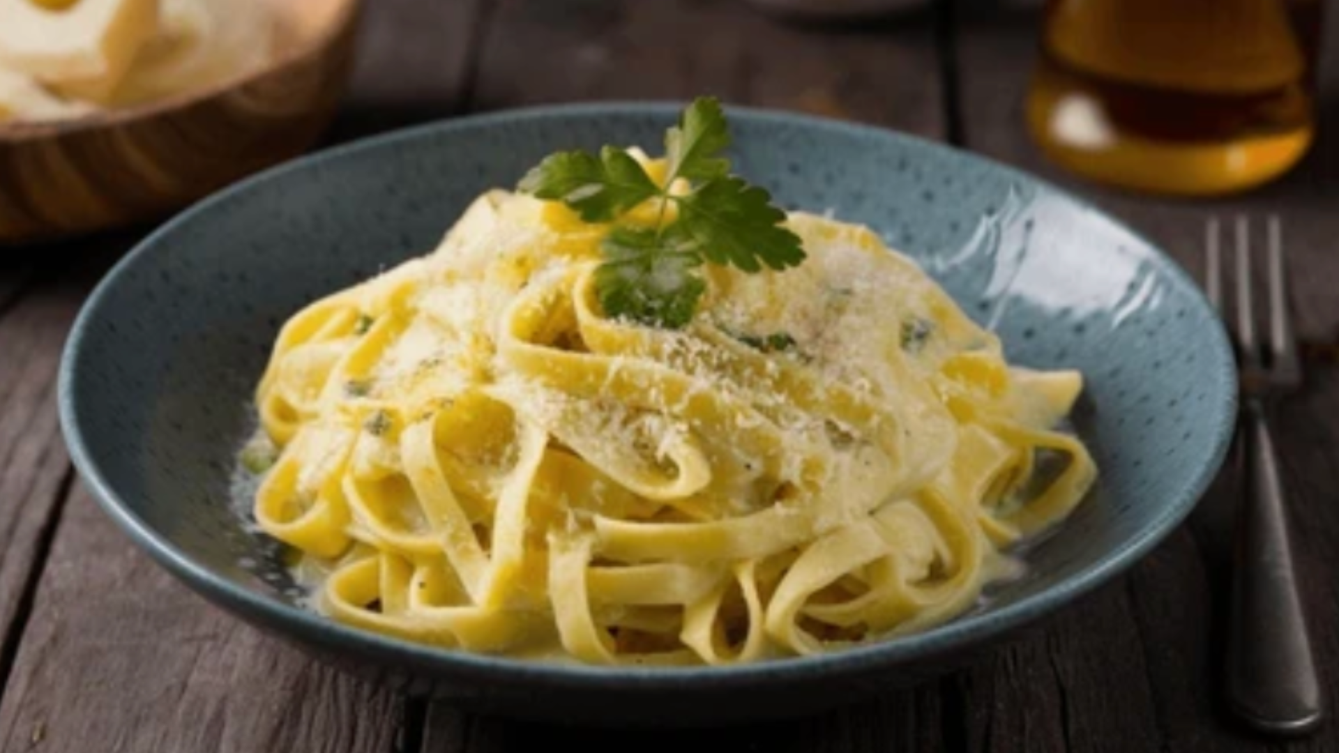 A blue bowl filled with a creamy pasta fettuccine alfredo dish garnished with fresh parsley and grated cheese.