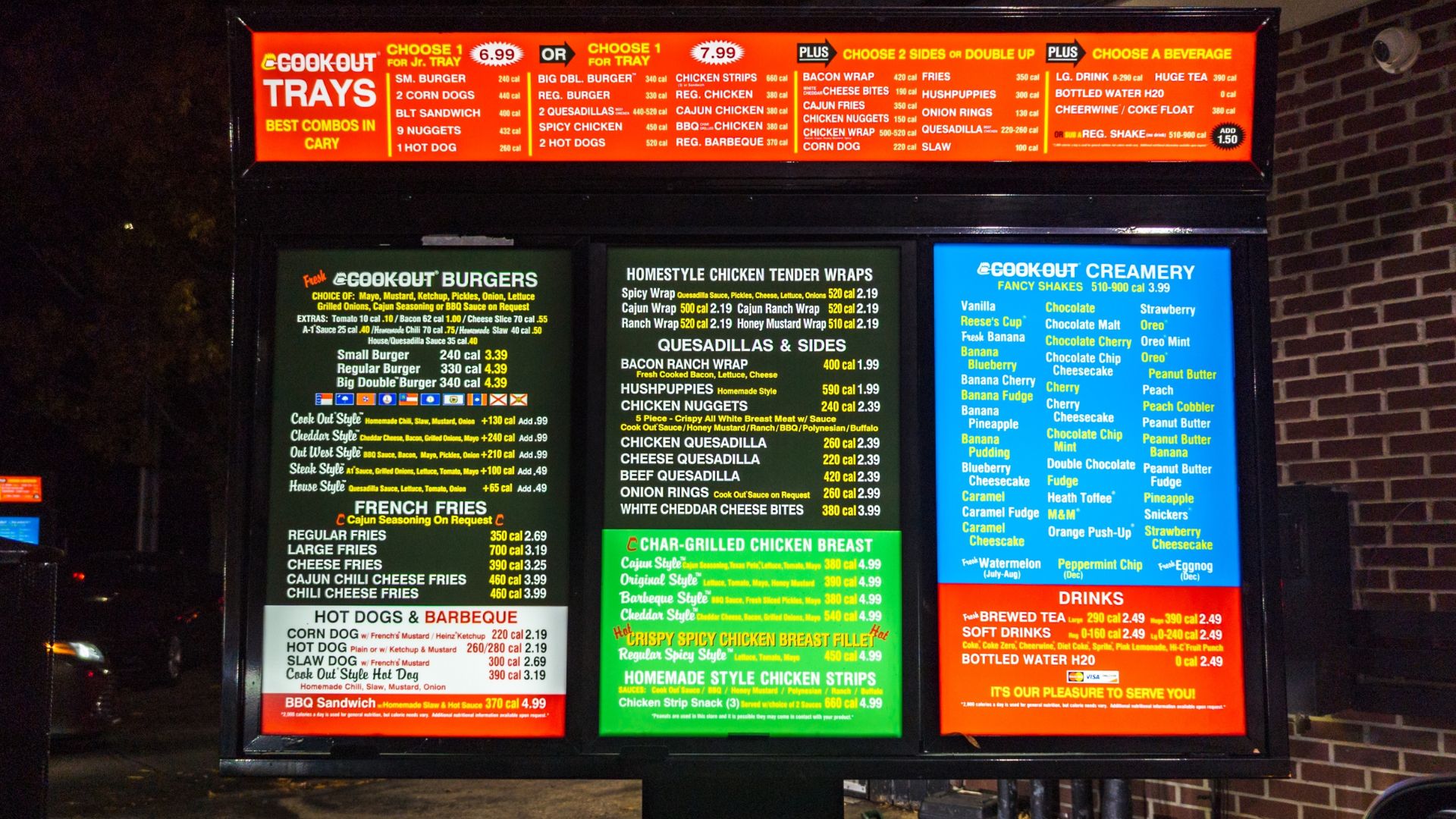 Fast food drive-thru menu board lit at night with food options displayed.