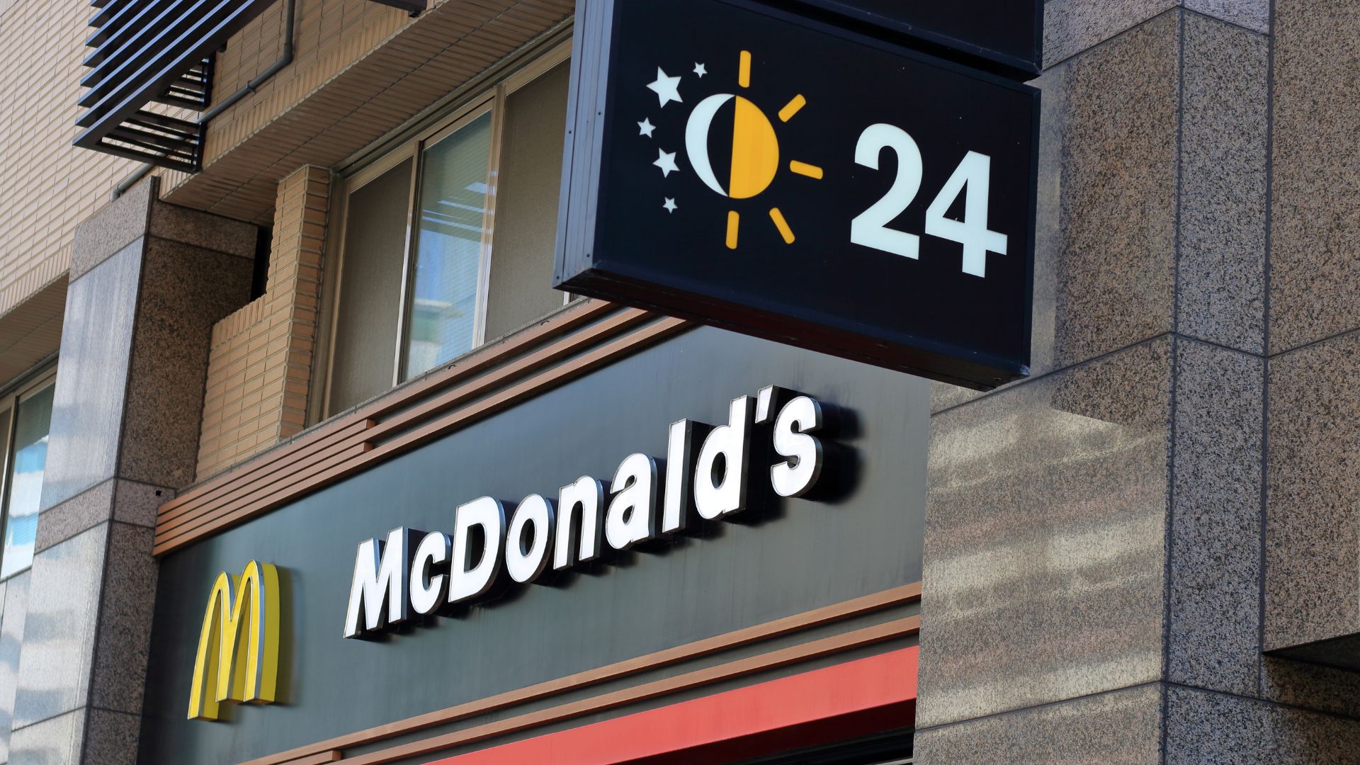 McDonald’s storefront with logo and 24-hour service sign on building exterior.