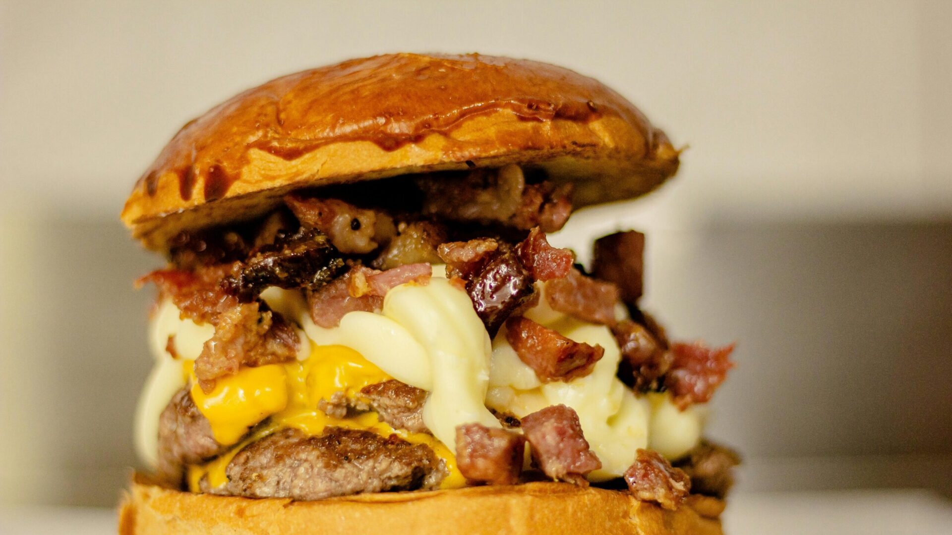 Close-up of a bacon cheeseburger with melted cheese and sesame seed bun.
