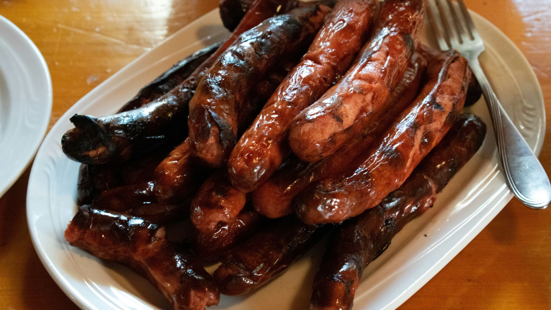 Plate of cooked sausage style hot dogs made from blended pork and beef