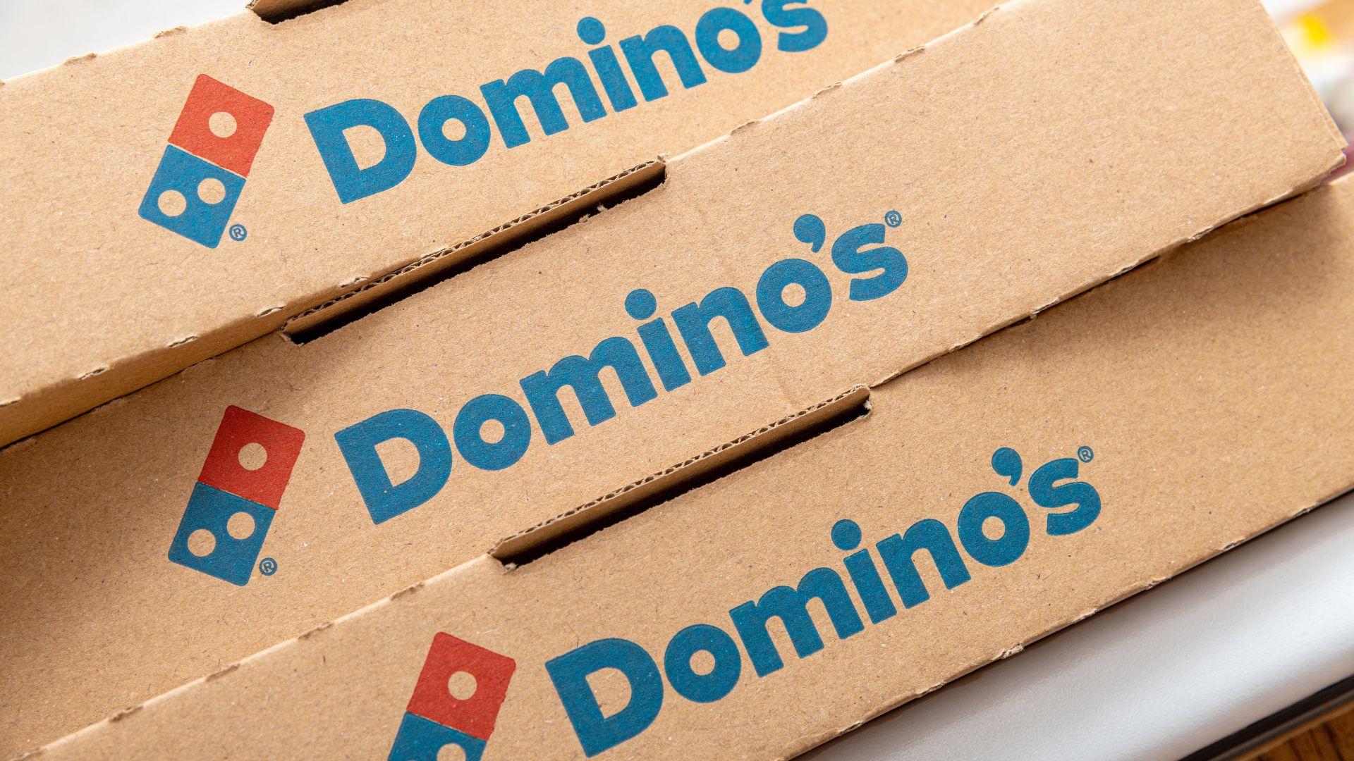 Domino’s pizza boxes stacked together with the Domino’s logo printed on the lids