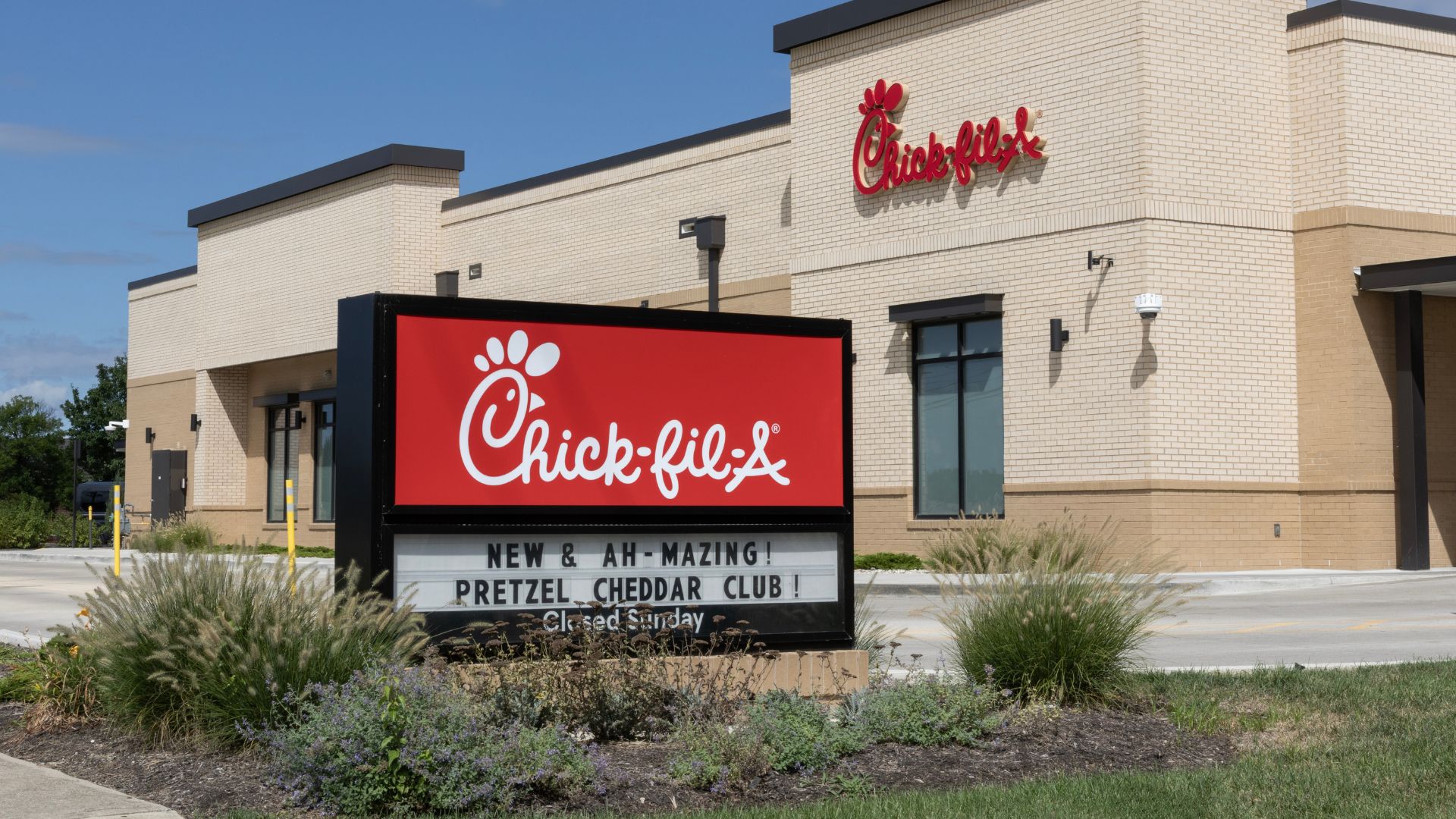 Chick-fil-A restaurant exterior with large roadside sign near parking lot.