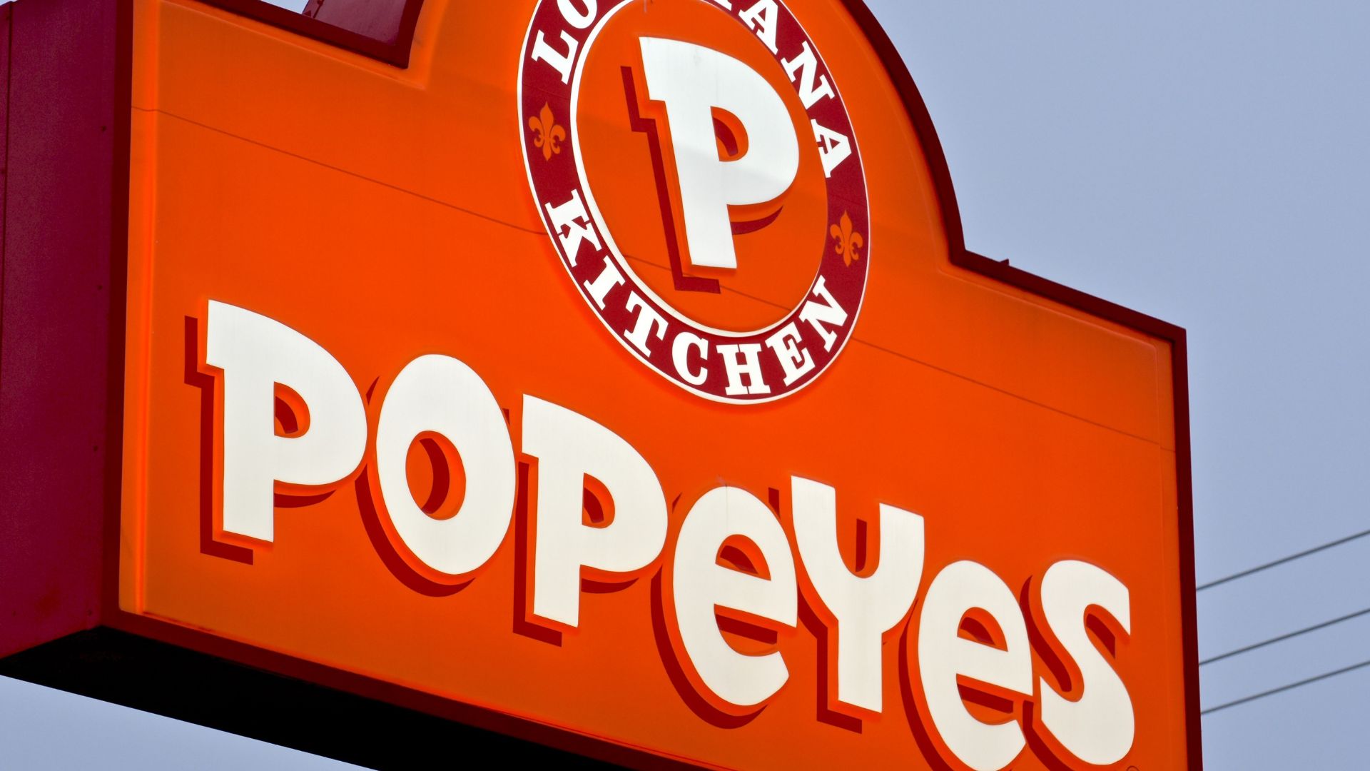 Popeyes restaurant exterior sign with logo on a bright orange background.