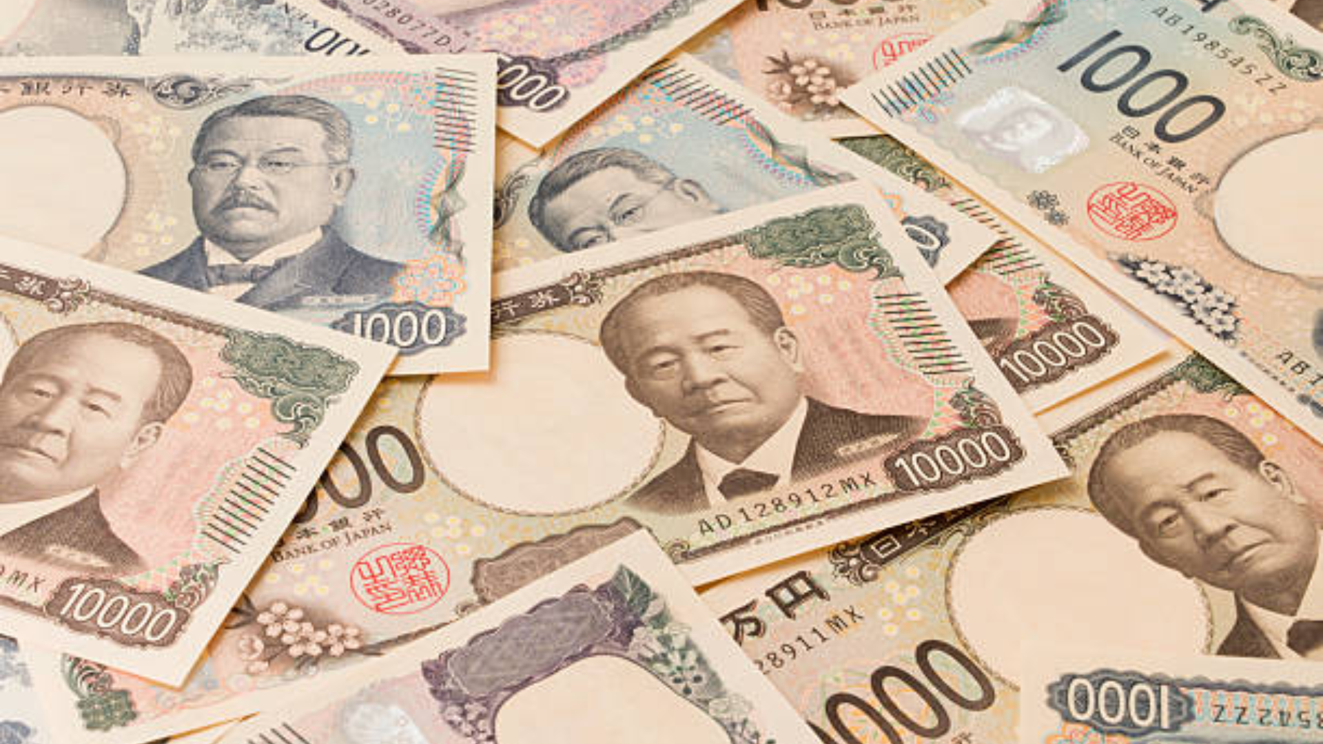 A scattered pile of new Japanese banknotes, including the 1,000 yen and 10,000 yen denominations, featuring updated portraits and anti-counterfeit designs.