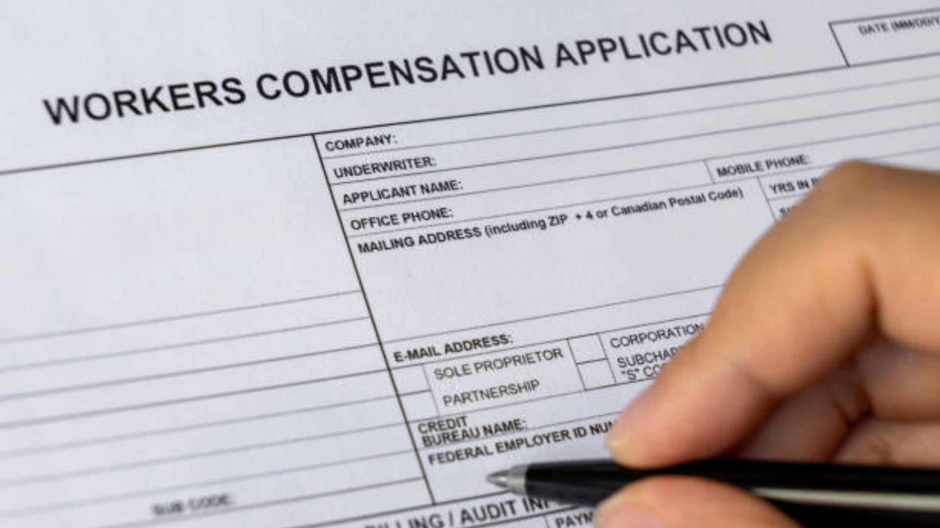 A close-up of a hand holding a pen and preparing to fill out a paper document.