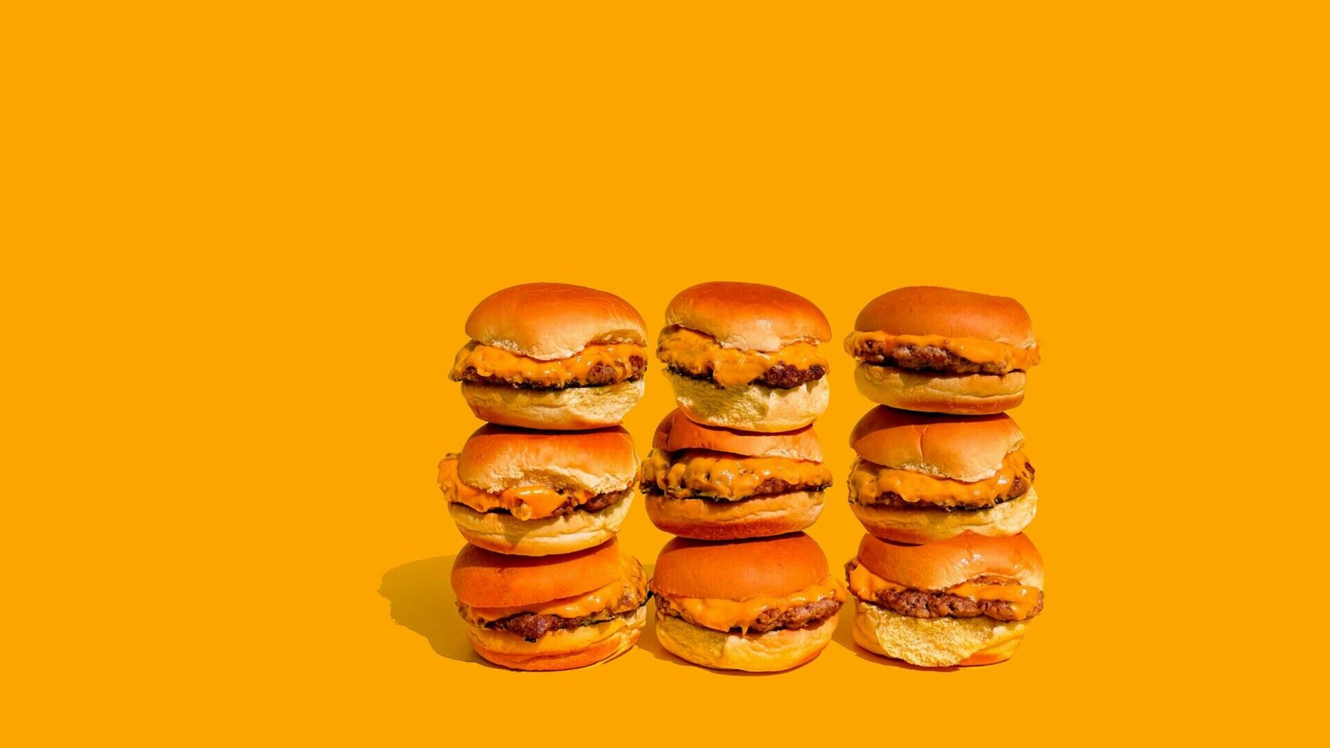 Stack of multiple burgers arranged closely together.